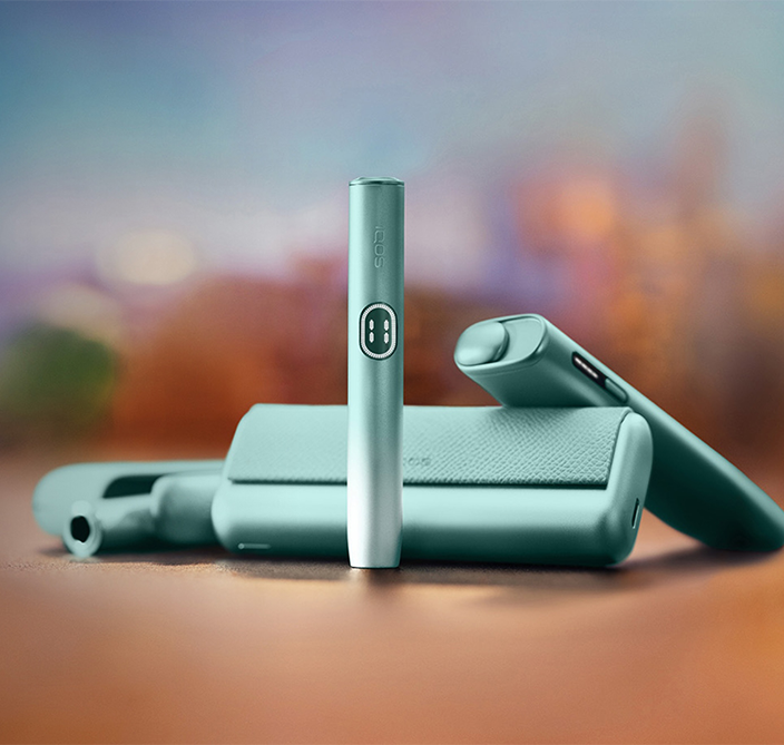 Equipamentos IQOS ILUMA i PRIME, IQOS ILUMA i e IQOS ILUMA i ONE em Azul Claro, em fundo desfocado.